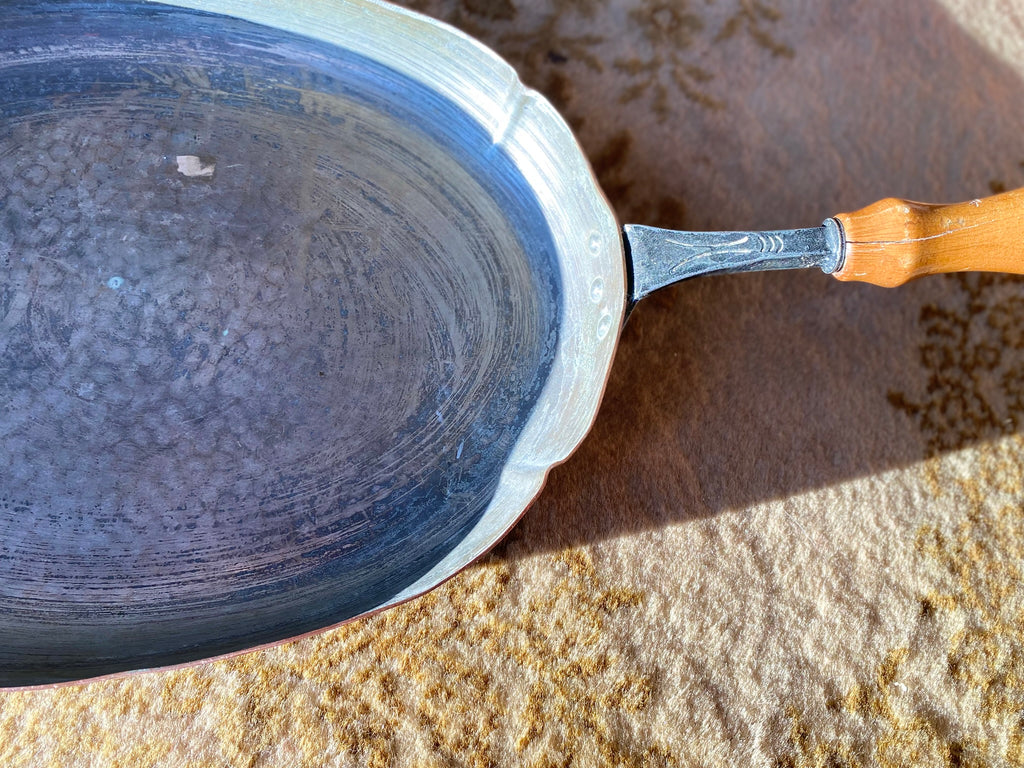 Old oval copper pan with wooden handle